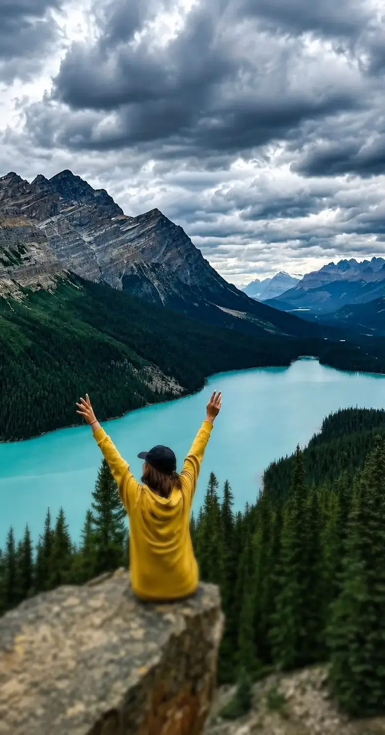 Studentessa con le braccia alzate su una roccia davanti a un lago di montagna